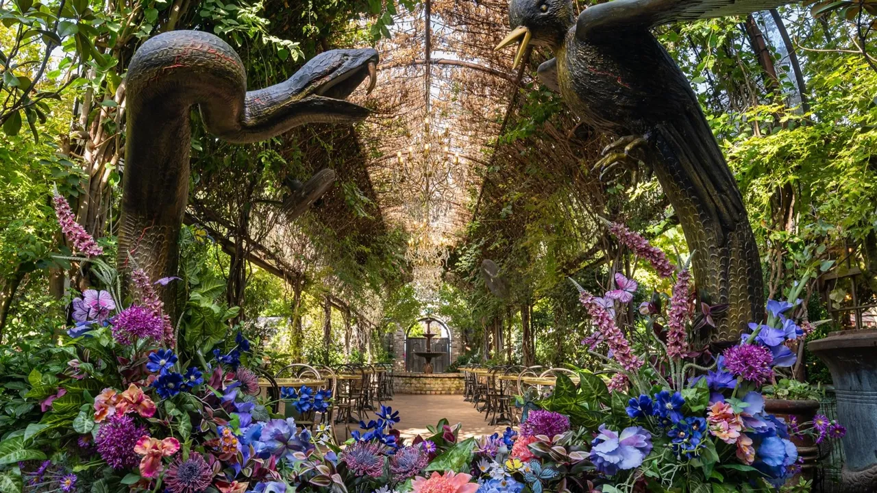The Sunrise on the Reaping floral installation at The Grounds of Alexandria — a carved mockingjay and snake facing each other above a bank of flowers